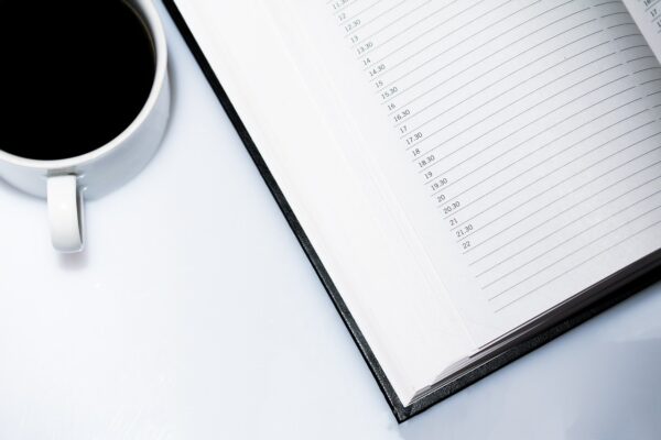 En kaffekopp intill en kalender, uppslagen på en sida utan noteringar.